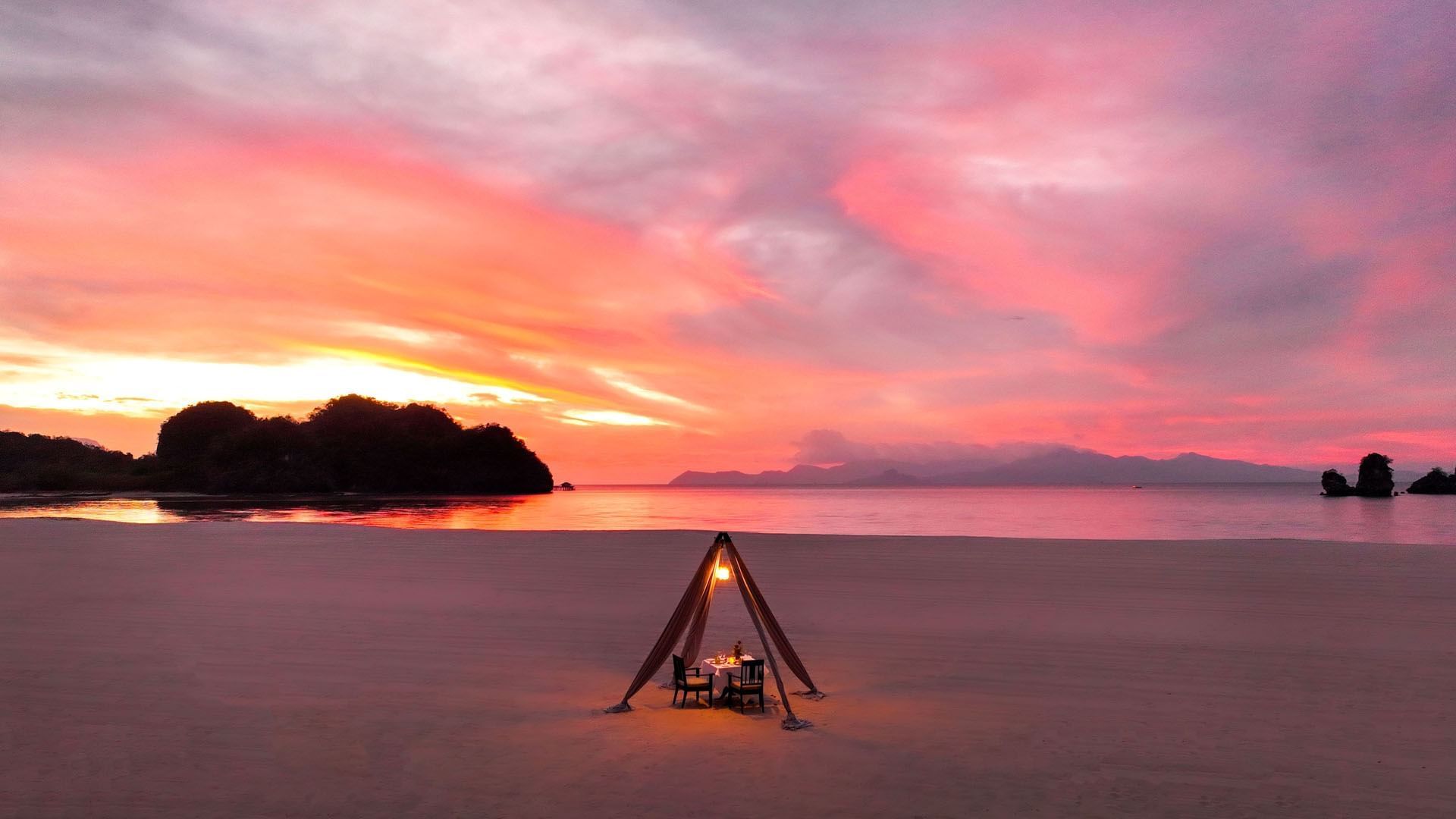 Wide sand flats at Tanjung Rhu beach at sunset, casuarina trees and limestone islets offshore